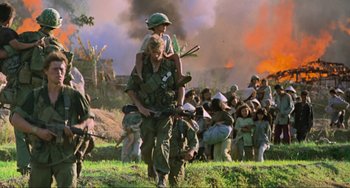 Movie still from “Platoon” (1986), directed by Oliver Stone – A man carrying a child on his back; Wide shot, Low angle