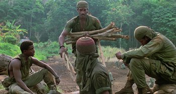 Movie still from “Platoon” (1986), directed by Oliver Stone – A group of men in the woods carrying sticks; Medium shot, Low angle