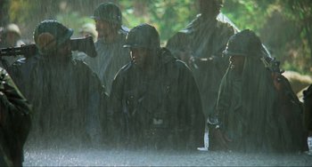 Movie still from “Platoon” (1986), directed by Oliver Stone – A group of men in uniforms are standing in the rain; Medium shot, High angle