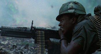 Movie still from “Platoon” (1986), directed by Oliver Stone – A man in fatigues is holding a gun; Medium shot, Low angle
