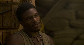 Movie still from “Platoon” (1986), directed by Oliver Stone – A man with a beard and a necklace is looking to his left; Close Up shot, Low angle