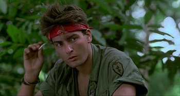 Movie still from “Platoon” (1986), directed by Oliver Stone – A man with a red bandanna sitting in the woods; Close Up shot, Low angle