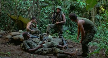 Movie still from “Platoon” (1986), directed by Oliver Stone – A group of men sitting on the ground in the woods; Wide shot, High angle