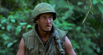 Movie still from “Platoon” (1986), directed by Oliver Stone – A man wearing a helmet and vest in the woods; Close Up shot, Low angle
