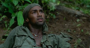 Movie still from “Platoon” (1986), directed by Oliver Stone – A man in a green shirt and a green hat looking up; Close Up shot, Low angle
