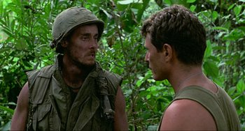Movie still from “Platoon” (1986), directed by Oliver Stone – Two men in the woods talking to each other; Close Up shot, Over the shoulder angle