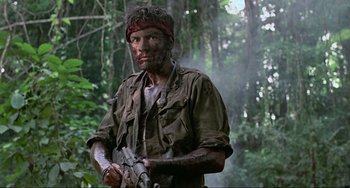 Movie still from “Platoon” (1986), directed by Oliver Stone – A man in the woods holding a gun; Medium shot, Low angle