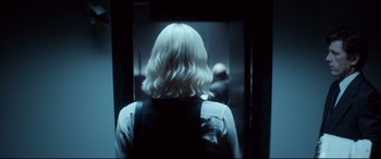 Movie still from “Atomic Blonde” (2017), directed by David Leitch – A woman with blonde hair is standing in an elevator; Close Up shot, Over the shoulder angle