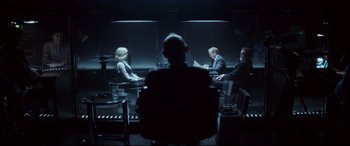 Movie still from “Atomic Blonde” (2017), directed by David Leitch – A group of people sitting at a table in a dark room; Wide shot, Over the shoulder angle