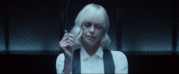 Movie still from “Atomic Blonde” (2017), directed by David Leitch – A woman smoking a cigarette while holding a cell phone; Close Up shot, Over the shoulder angle