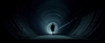 A man is walking in a dark tunnel