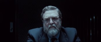 Movie still from “Atomic Blonde” (2017), directed by David Leitch – An older man with a beard and glasses; Close Up shot, Over the shoulder angle