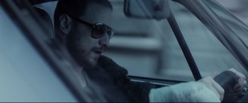 A man driving in a car wearing sunglasses