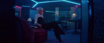 Movie still from “Atomic Blonde” (2017), directed by David Leitch – A woman sitting on top of a couch in a room; Wide shot, Low angle