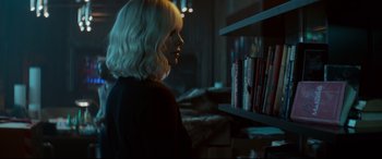 Movie still from “Atomic Blonde” (2017), directed by David Leitch – A woman standing in front of a book shelf; Medium shot, Over the shoulder angle
