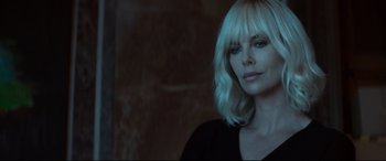 Movie still from “Atomic Blonde” (2017), directed by David Leitch – A woman with blonde hair is posing for a picture; Close Up shot, Over the shoulder angle