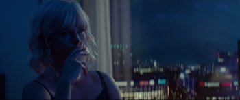 A woman with blonde hair sitting in front of a window at night