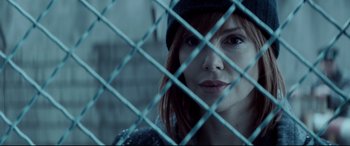 Movie still from “Atomic Blonde” (2017), directed by David Leitch – A woman with a hat is looking through a fence; Close Up shot, Over the shoulder angle