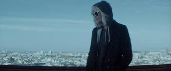 Movie still from “Atomic Blonde” (2017), directed by David Leitch – A woman in a hooded jacket looking out over a city; Medium shot, Low angle