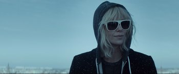 Movie still from “Atomic Blonde” (2017), directed by David Leitch – A woman wearing sunglasses and a hooded jacket; Close Up shot, Over the shoulder angle