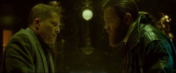 Movie still from “Atomic Blonde” (2017), directed by David Leitch – Two men are standing next to each other in front of a clock; Close Up shot, Low angle