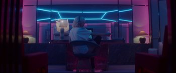 Movie still from “Atomic Blonde” (2017), directed by David Leitch – A woman sitting in a chair in front of a computer monitor; Wide shot, Low angle