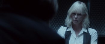 Movie still from “Atomic Blonde” (2017), directed by David Leitch – A woman with blonde hair wearing a white shirt and black tie; Close Up shot, Over the shoulder angle