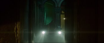 Movie still from “Atomic Blonde” (2017), directed by David Leitch – A person is walking in a dark hallway with headlights on; Wide shot, Low angle