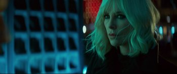 Movie still from “Atomic Blonde” (2017), directed by David Leitch – A beautiful woman with blonde hair standing in front of a building; Close Up shot, Over the shoulder angle