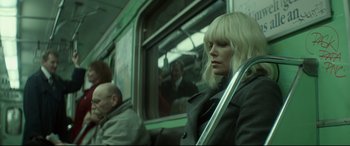 Movie still from “Atomic Blonde” (2017), directed by David Leitch – A woman sitting on a train holding onto a handle; Medium shot, Low angle
