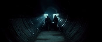 Movie still from “Atomic Blonde” (2017), directed by David Leitch – Two people are walking down a tunnel in the dark; Wide shot, Low angle