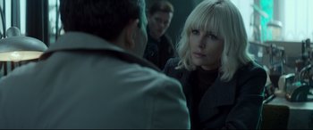 Movie still from “Atomic Blonde” (2017), directed by David Leitch – A group of people standing next to each other in a room; Close Up shot, Over the shoulder angle