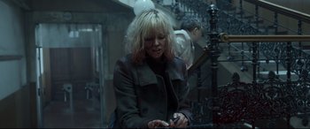 Movie still from “Atomic Blonde” (2017), directed by David Leitch – A woman sitting on a bench looking at her cell phone; Medium shot, High angle