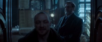 Movie still from “Atomic Blonde” (2017), directed by David Leitch – A man in a suit and tie standing next to another man in a suit and tie; Medium shot, Over the shoulder angle