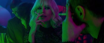 Movie still from “Atomic Blonde” (2017), directed by David Leitch – A woman smoking a cigarette in a dark room; Close Up shot, Over the shoulder angle