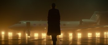 Movie still from “Atomic Blonde” (2017), directed by David Leitch – A person standing in front of an airplane at an airport; Wide shot, Low angle