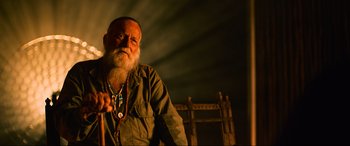 Movie still from “Poker Face” (2022), directed by Russell Crowe – An old man with a beard and a long white beard is holding a cane; Close Up shot, Low angle