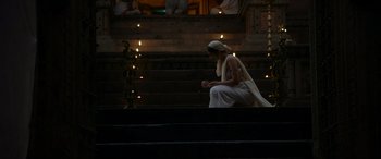 A woman sitting on some steps wearing a long white dress