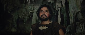 A man with a beard and blood on his face looking up