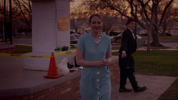 Movie still from “Popovich: Road to Hollywood” (2021), directed by Gregory Popovich – A woman in a blue dress walking down a sidewalk; Medium shot, Over the shoulder angle