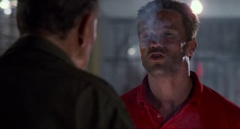 Movie still from “Predator” (1987), directed by John McTiernan – A man smoking a cigarette in front of another man; Close Up shot, Over the shoulder angle
