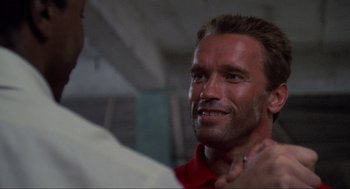 Movie still from “Predator” (1987), directed by John McTiernan – A man looking at the camera; Close Up shot, Low angle