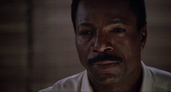 Movie still from “Predator” (1987), directed by John McTiernan – A person wearing a white shirt; Close Up shot, Low angle