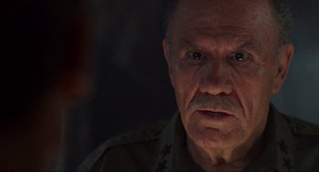 Movie still from “Predator” (1987), directed by John McTiernan – An old man with a beard and mustache looking at the camera; Close Up shot, Over the shoulder angle
