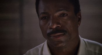 Movie still from “Predator” (1987), directed by John McTiernan – A person wearing a white shirt; Close Up shot, Low angle