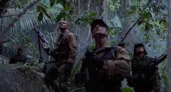 Movie still from “Predator” (1987), directed by John McTiernan – A couple of men standing on top of a tree; Medium shot, Low angle