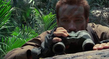 Movie still from “Predator” (1987), directed by John McTiernan – A man holding a pair of binoculars in his hands; Close Up shot, Low angle