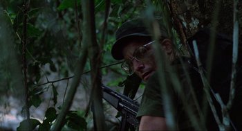 Movie still from “Predator” (1987), directed by John McTiernan – A man with a gun in the middle of a forest; Close Up shot, Low angle