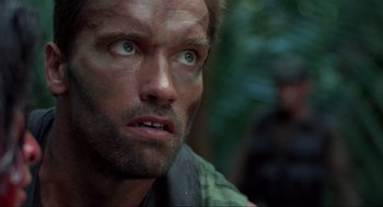 Movie still from “Predator” (1987), directed by John McTiernan – A man's face in the woods; Close Up shot, Low angle