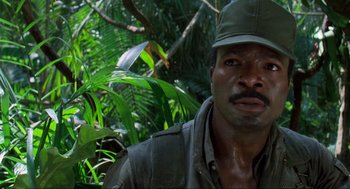 Movie still from “Predator” (1987), directed by John McTiernan – A person wearing a hat in the woods; Close Up shot, Low angle